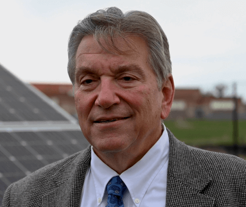Headshot of Doug Renkosik in front of solar panels.