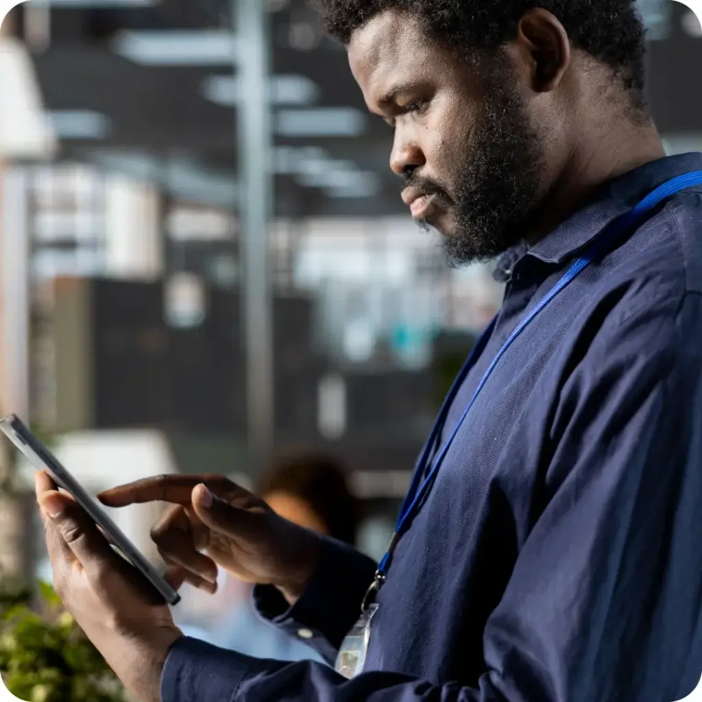 A photo depicting a janitorial inspector in the field looking at a report on a tablet.